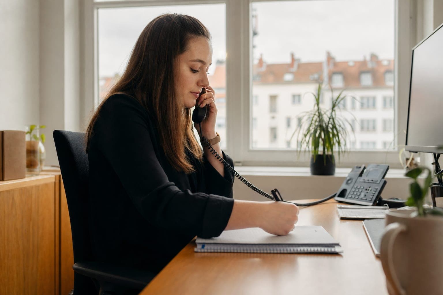 Recruiterin im Telefonat mit Notizblock am Schreibtisch